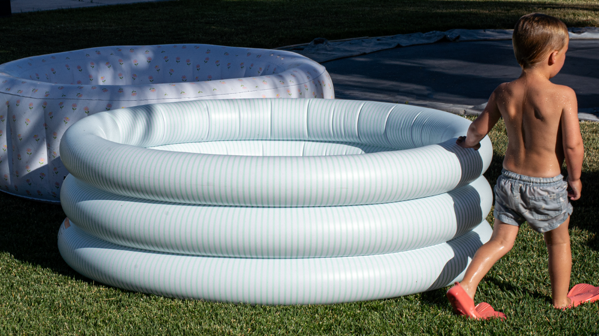 Child playing with kiddie pools in backyard