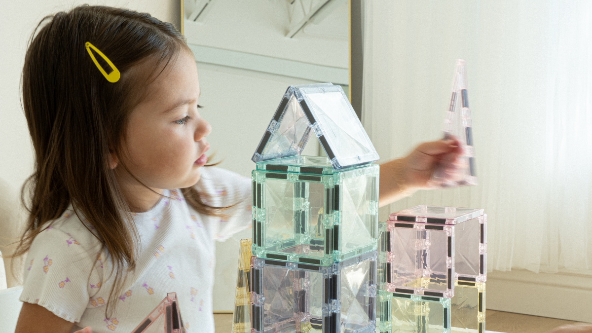 Toddler playing with open ended wooden toys and magnetic tiles in modern playroom