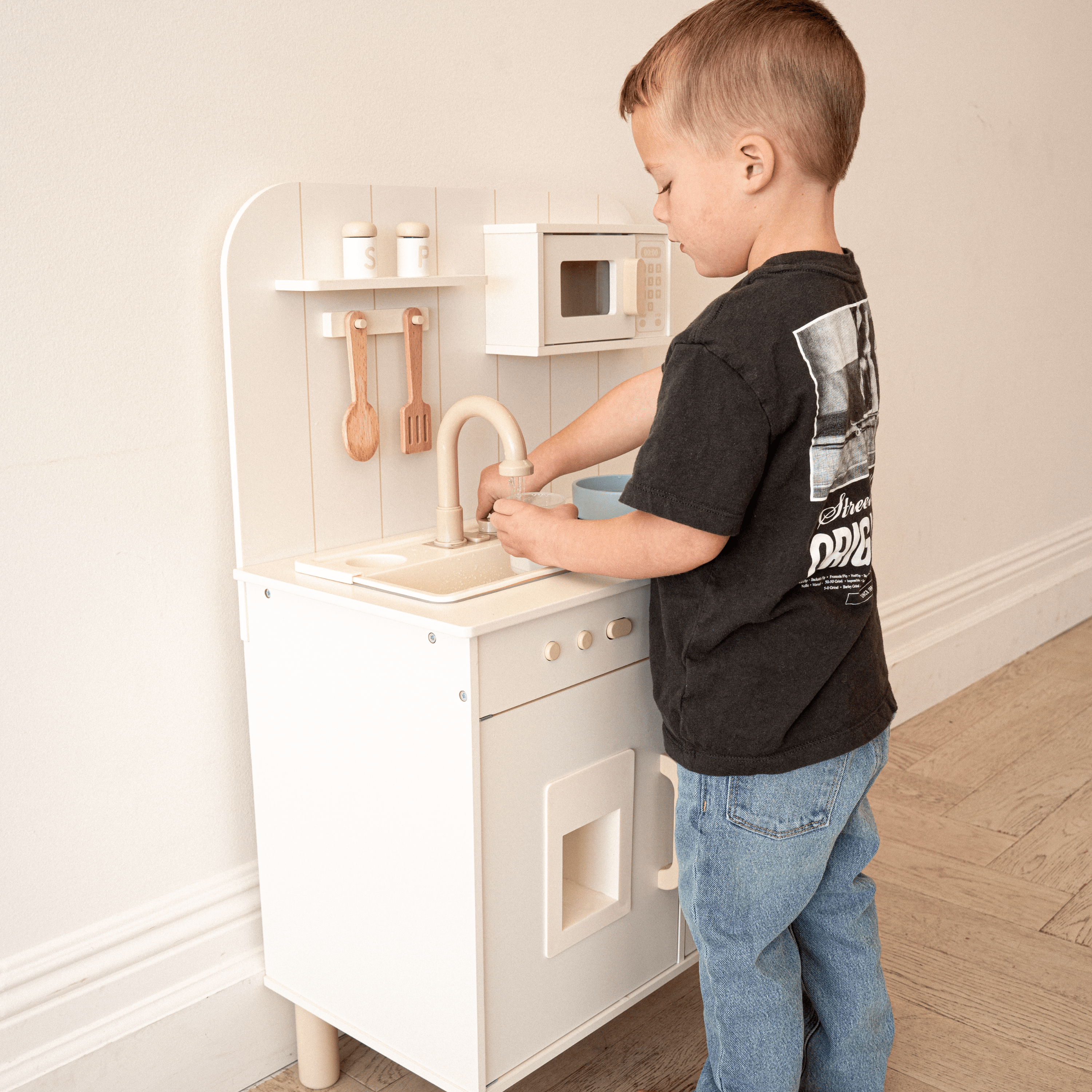 Toddler playing with wooden kitchen set