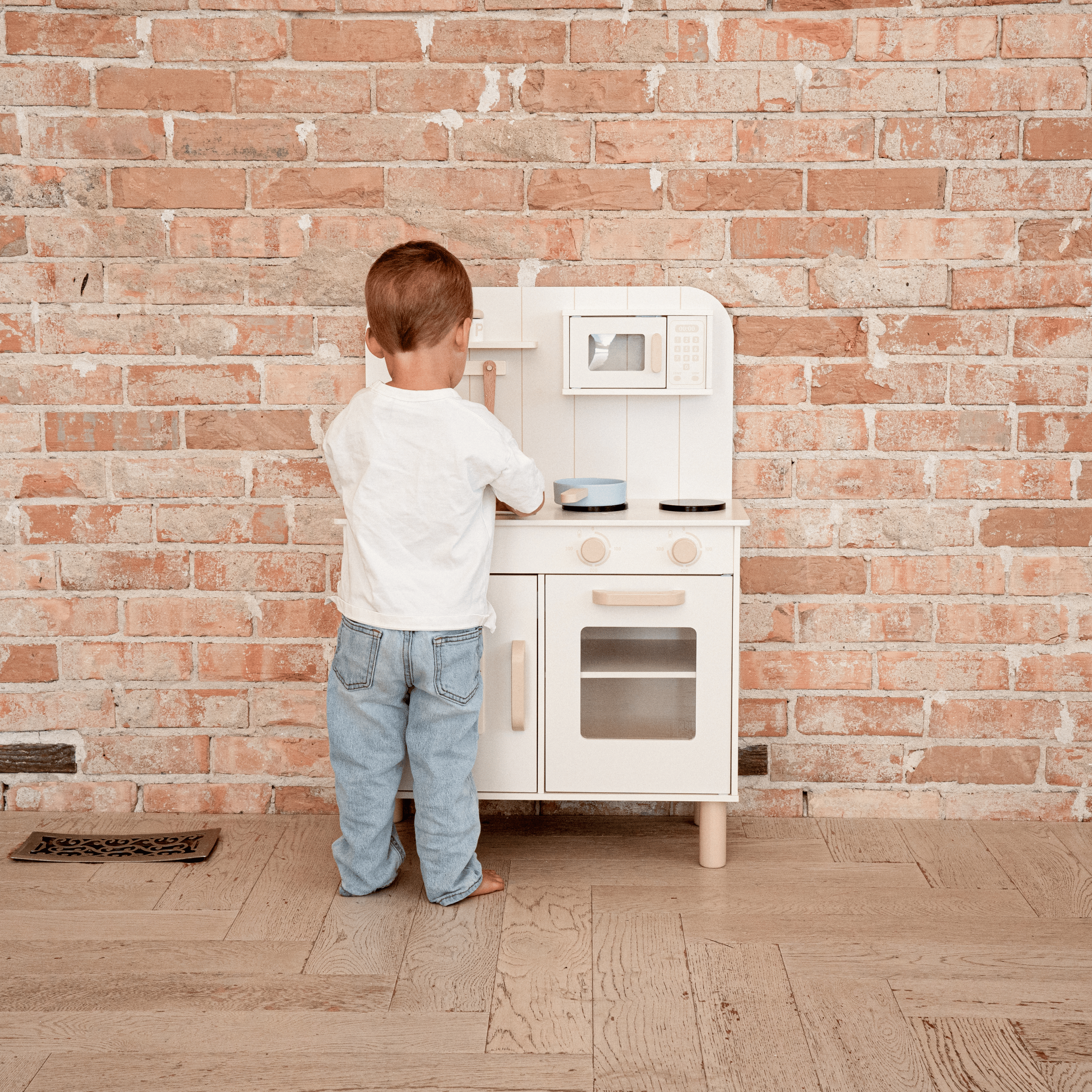 Toddler playing with wooden kitchen set