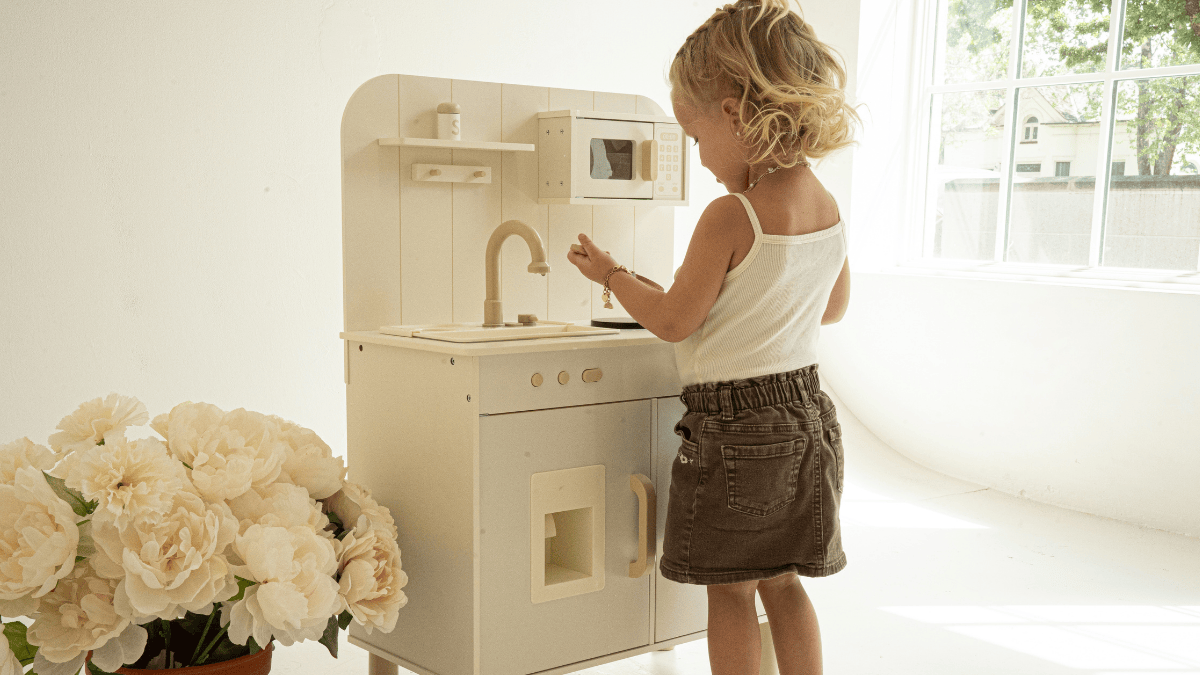 Square House play kitchen in neutral living room with toddler cooking pretend food