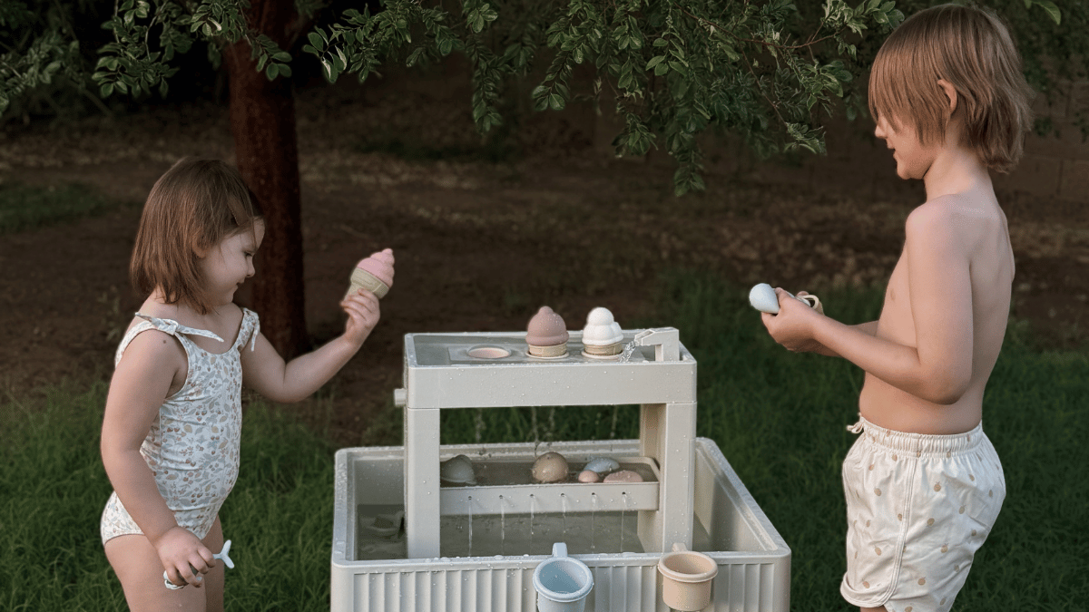 Two children playing with aesthetic water table in backyard, ice cream cone toys