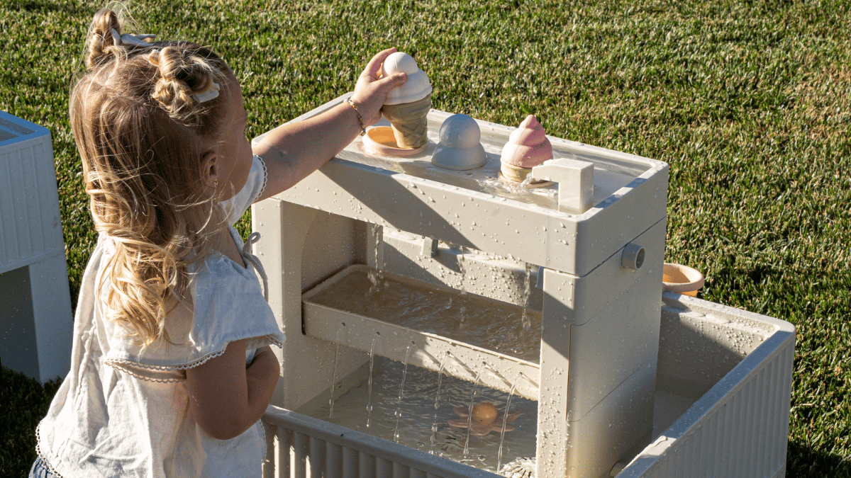 Toddler playing outside with a water table during screen-free summer activities
